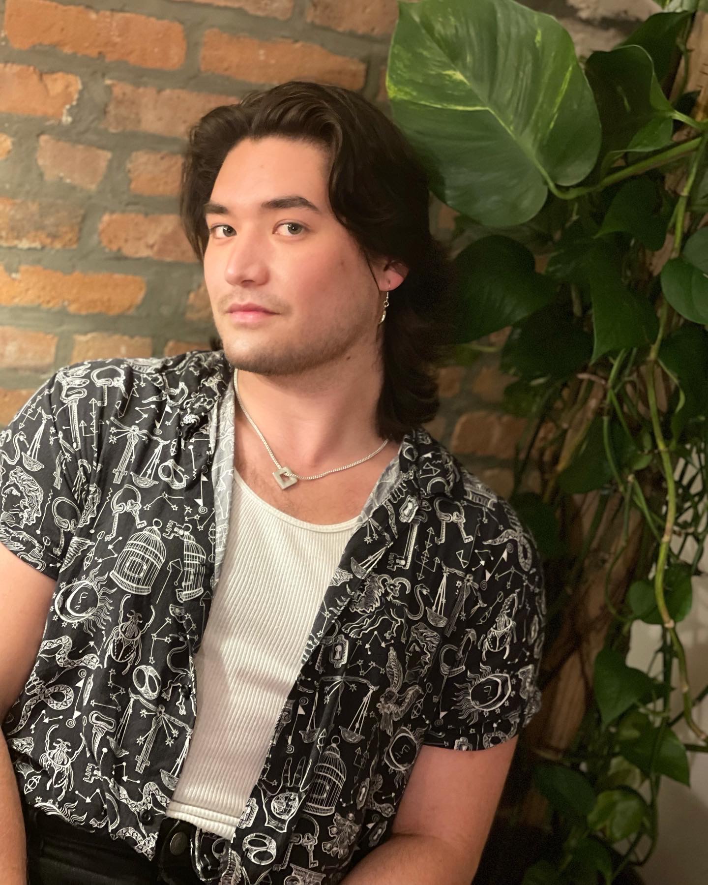 Jasen Miyamoto, late 20s man sitting in front of brick wall